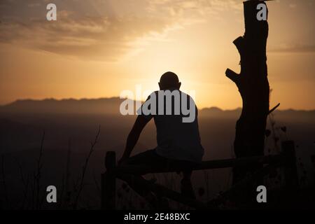 Silhouette di uomo che si affaccia sulle montagne al tramonto Foto Stock