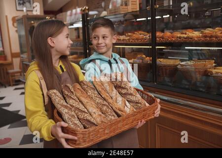 I piccoli panettieri affascinanti che vendono il pane delizioso al loro caffè della panetteria della famiglia, spazio di copia Foto Stock