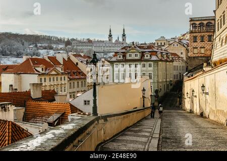 Turisti a piedi in via vuota, Praga, Repubblica Ceca.Praga inverno panorama.Snowy giorno in città. Incredibile paesaggio urbano europeo freddo Weather.Romantic a. Foto Stock