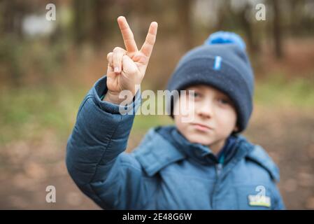 Il ragazzo mostra due dita come simbolo della vittoria Foto Stock