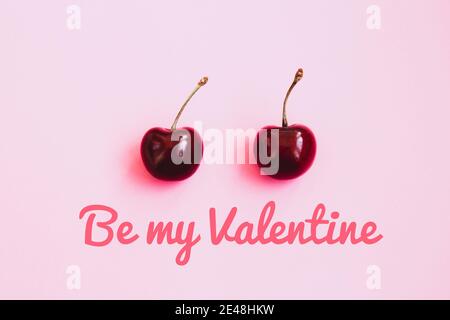 Due ciliegie mature su sfondo rosa chiaro. Concetto di San Valentino. Iscrizione sia il mio Valentine Foto Stock