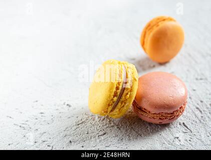 Tre deliziosi macaroni francesi su un tavolo grigio con copia spazio Foto Stock