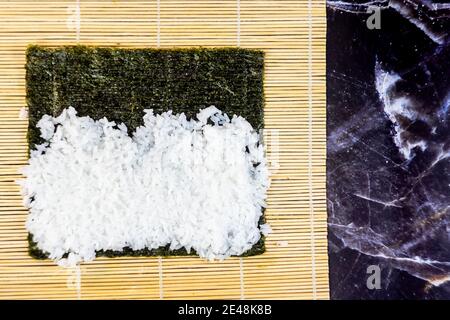 sushi fatto in casa tradizionale giapponese maestro di fare sani panini maki con gamberi cetrioli carote pesce Foto Stock