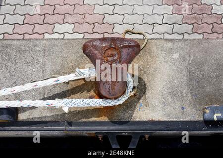 Hawser intorno ad un bollard arrugginito su una banchina di cemento Foto Stock