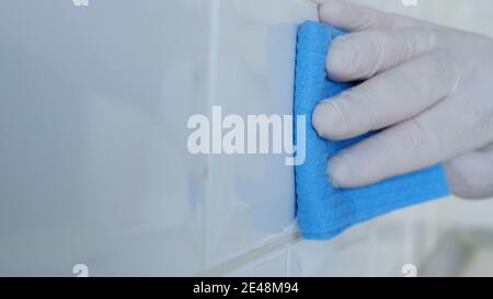 Immagine closeup con le mani che indossano i guanti domestici bianchi di protezione che Pulisce e disinfetta la cucina Faience Foto Stock