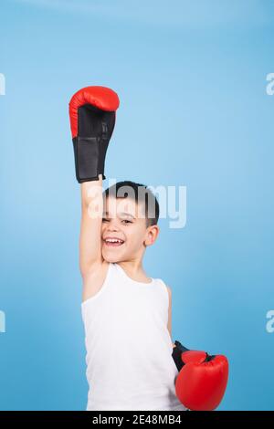 un bambino boxer alza i suoi pugni in alto come un vincitore. Concetto di vittoria Foto Stock