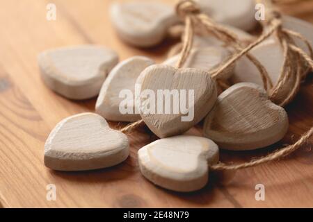 Gruppo di cuori scolpiti e fatti di legno scheggiato su un tavolo con luce naturale. Immagine romantica non filtrata, piena d'amore per San Valentino. Foto Stock