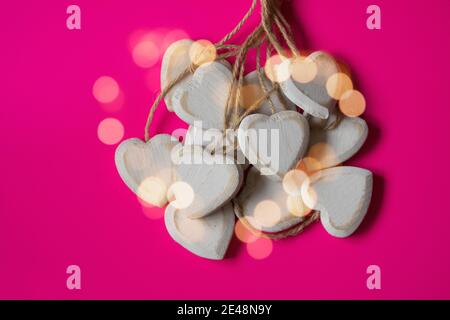 Gruppo di cuori intagliati e fatti di legno scheggiato su sfondo rosa con luce naturale. Immagine romantica non filtrata, piena d'amore per San Valentino. Foto Stock