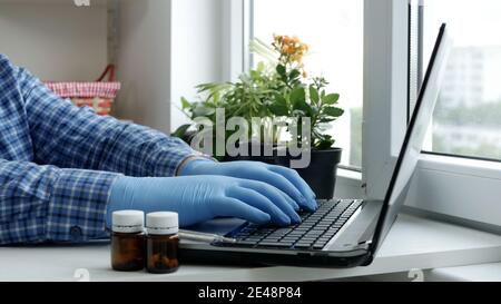 Sick Man lavorare con il laptop indossando guanti protettivi Foto Stock