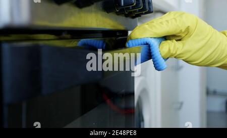 Closeup uomo mani indossare White Protective Household Guanti pulisce il Fornello porta piano cottura e i suoi accessori Foto Stock