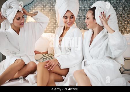 Signore in accappatoi che riposano e chiacchierano sul letto Foto Stock