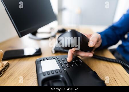 Primo piano di un uomo d'affari di composizione a mano numero di telefono da fare Chiamata telefonica in ufficio Foto Stock