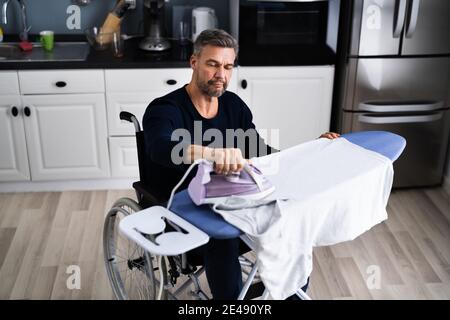 Uomo disabili in abiti da stiro per sedie a rotelle Foto Stock