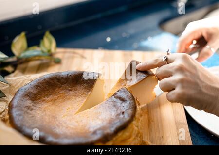 Una mano che prende una porzione di cheesecake fatto in casa Foto Stock
