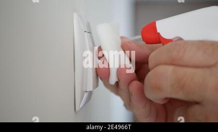 Uomo pulizia e disinfezione interruttore luce dalla sala ufficio Utilizzo di disinfettanti contro i virus Covid-19 Foto Stock