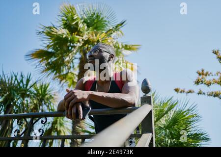 Il giovane si appoggia sulla ringhiera, facendo una pausa di pensiero Foto Stock