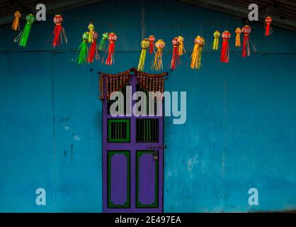 Parete blu chiaro e porta di colore viola o blu scuro con lanterne decorate con colori Foto Stock