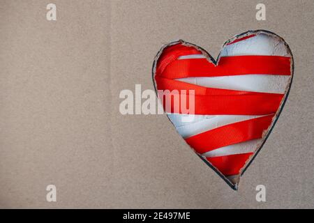 Il cartone tagliato a forma di cuore giace su un nastro rosso. Il concetto di San Valentino. Spazio per il testo Foto Stock