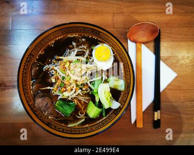 Ciotola di zuppa di Ramem di Japanes con cucchiaio di legno e bastoncini di pollo. Foto Stock