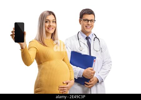 Donna incinta che tiene un telefono cellulare e sta accanto a. un medico maschile con una cartella isolata su sfondo bianco Foto Stock