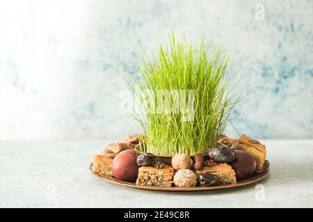 Vassoio tradizionale Novruz con semeni o sabzi di erba di grano verde, dolci e pakhlava di frutta secca su sfondo bianco. Equinox primaverile, copia dell'Azerbaigian sp Foto Stock