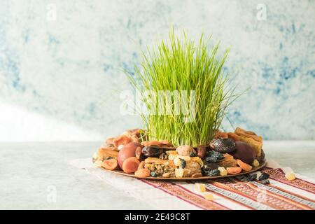 Vassoio tradizionale Novruz con semeni o sabzi di erba di grano verde, dolci e pakhlava di frutta secca su sfondo bianco. Equinox primaverile, copia dell'Azerbaigian sp Foto Stock