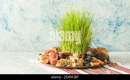 Vassoio tradizionale Novruz con semeni o sabzi di erba di grano verde, dolci e pakhlava di frutta secca su sfondo bianco. Equinox primaverile, copia dell'Azerbaigian sp Foto Stock