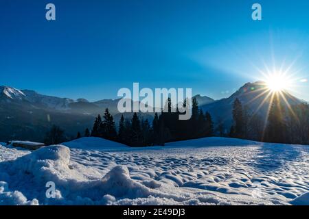 Paesaggio al tramonto con montagne innevate e prati innevati, alberi e foreste. Sonnenuntergang im Schneebedeckten Bäume Foto Stock