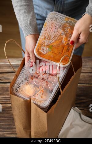 Le mani femminili da vicino tirano il cibo in sacchetti di plastica dalla borsa. Ordinare il cibo a casa. Consegna di cibo. Foto Stock