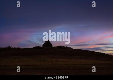 Piccola casa all'orizzonte durante un tramonto a Guernsey Foto Stock