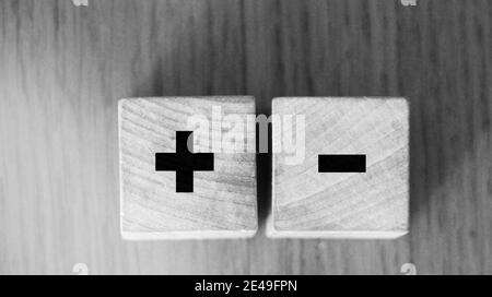 I segni più e meno sui cubetti di legno sul tavolo di legno. Concetto di soluzione aziendale. Foto Stock