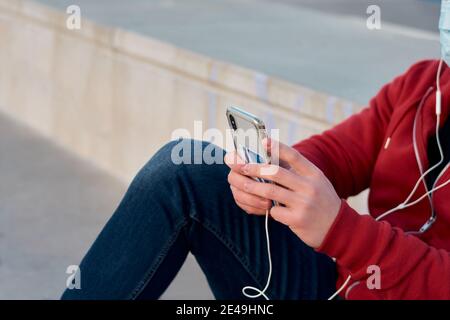 L'uomo studentesco irriconoscibile usa il suo telefono in un campo da basket Foto Stock