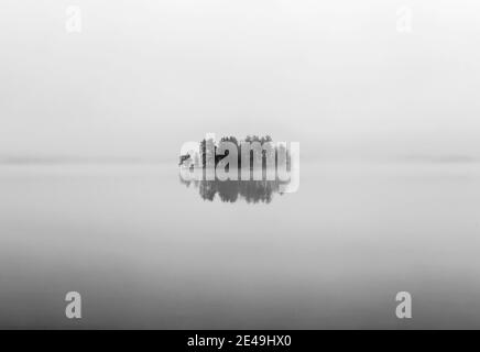 L'isola di Lone si riflette in acque calme del lago nel giorno della nebbia, Maine Foto Stock