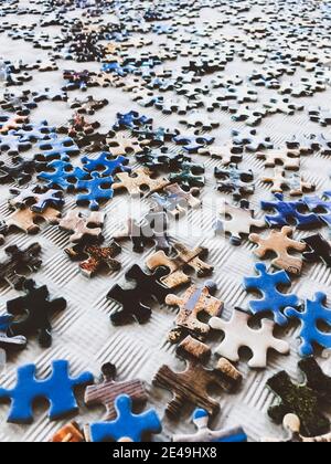 pezzi di puzzle disordinati su un tavolo bianco Foto Stock