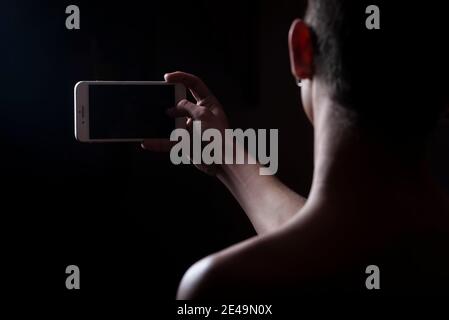 giovane uomo che prende un selfie nell'ombra Foto Stock