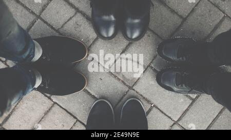Vista dall'alto dei piedi degli amici. I giovani fanno un cerchio e mostrano le loro scarpe all'aperto, la gente rally. Foto Stock