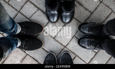 Vista dall'alto dei piedi degli amici. I giovani fanno un cerchio e mostrano le loro scarpe. Riunire le persone. Gli amici mostrano le gambe. Foto Stock