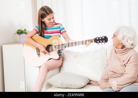 Nonna che ascolta la nipote che suona la chitarra Foto Stock