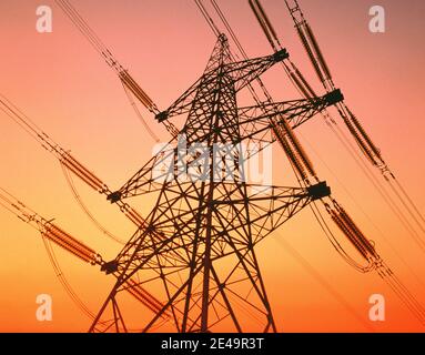 Vista ad angolo basso della torre di piloni elettrici che sovrasta le torri contro il cielo dell'alba al tramonto Foto Stock