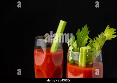 Vista dall'alto di due bicchieri di cristallo con cocktail Bloody Mary, messa a fuoco selettiva, su sfondo nero, orizzontale, con spazio per la copia Foto Stock
