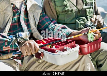 Uomo che utilizza Tackle Box e la preparazione di pesca polo Foto Stock