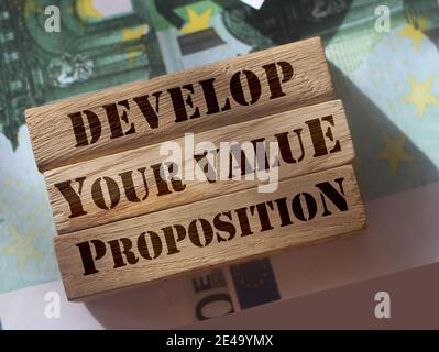 Sviluppa la tua proposta valur su blocchi di legno in piedi su 100 euro fatture. Concetto di marketing aziendale. Foto Stock