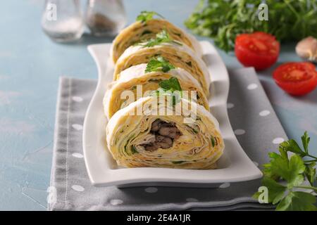 Rotolo di lavasch con spratti, formaggio cremoso, cetriolo e uova su sfondo azzurro. Primo piano Foto Stock