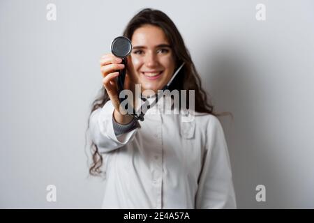 Donna smiley medico chirurgo con stetoscopio su sfondo bianco. Medecine professionale. Advert per clinica medica Foto Stock