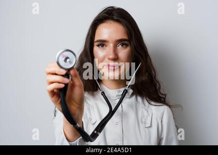 Donna smiley medico chirurgo con stetoscopio su sfondo bianco. Medecine professionale. Advert per clinica medica Foto Stock