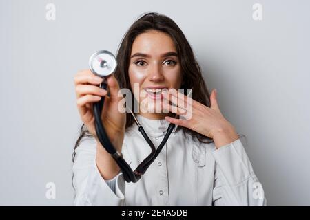 Donna smiley medico chirurgo con stetoscopio su sfondo bianco. Medecine professionale. Advert per clinica medica Foto Stock