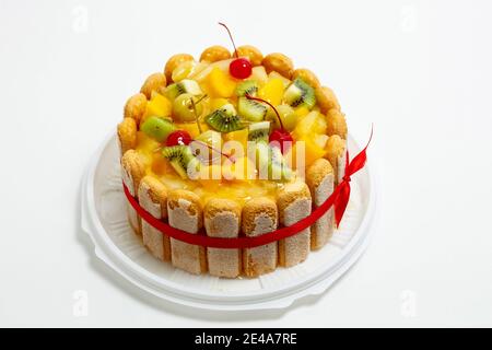 Torta con ciliegie kiwi e ananas. Torta su sfondo bianco Foto Stock