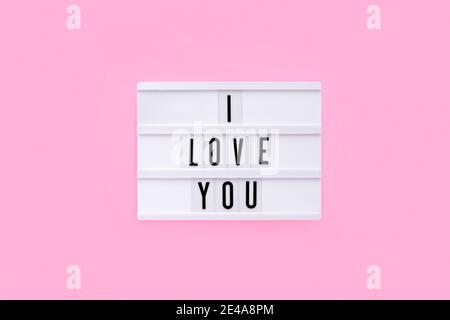 I Love You testo su lightbox bianco su sfondo rosa chiaro. Vista dall'alto. Concetto di piatto per San Valentino. Banner. Tema dell'amore Foto Stock