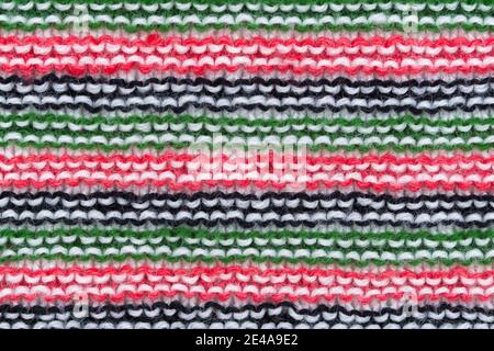 Primo piano del motivo lavorato a mano in lana di maglia in rosso, bianco, nero e verde. Foto Stock