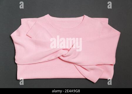 Pullover lavorato a maglia di colore rosa chiaro e alla moda sfondo grigio in stile flay lay Foto Stock